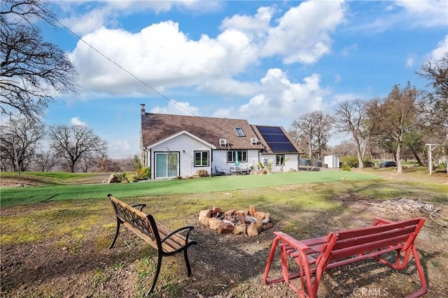 rear view of property featuring a yard and solar panels