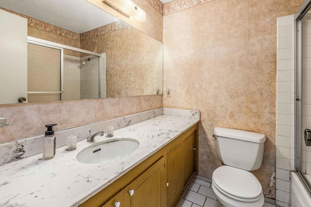 full bathroom with toilet, tile patterned floors, bath / shower combo with glass door, and vanity