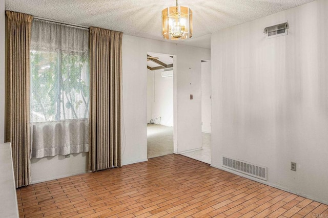 empty room with a chandelier and a textured ceiling