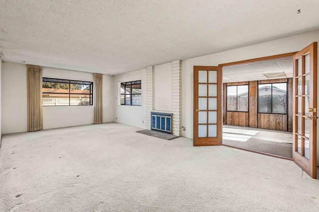 unfurnished living room with a fireplace, french doors, and a textured ceiling