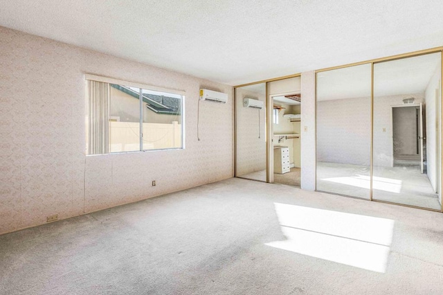 unfurnished bedroom featuring multiple closets, carpet, and a wall mounted air conditioner