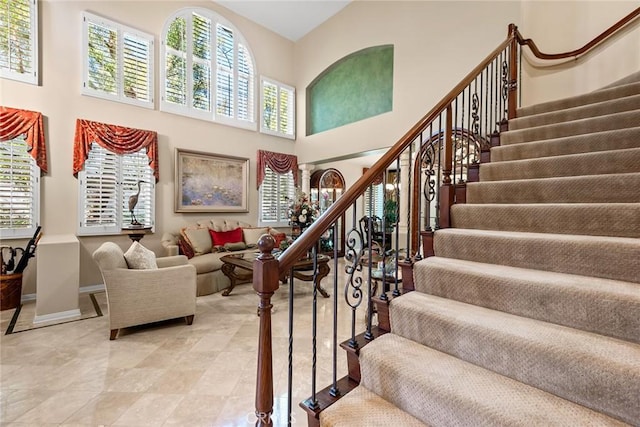 staircase featuring a towering ceiling and a healthy amount of sunlight