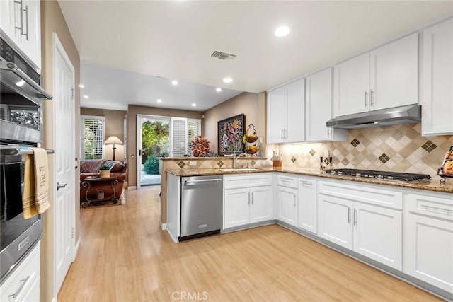 kitchen with tasteful backsplash, white cabinetry, appliances with stainless steel finishes, and kitchen peninsula