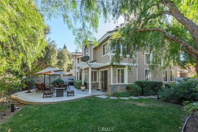 back of house featuring a fire pit, a yard, and a patio area