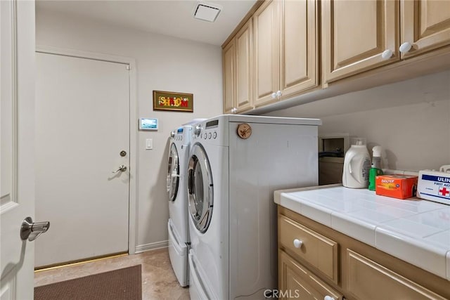 laundry area with separate washer and dryer and cabinets