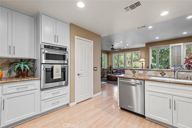 kitchen with sink, light stone counters, backsplash, stainless steel appliances, and white cabinets