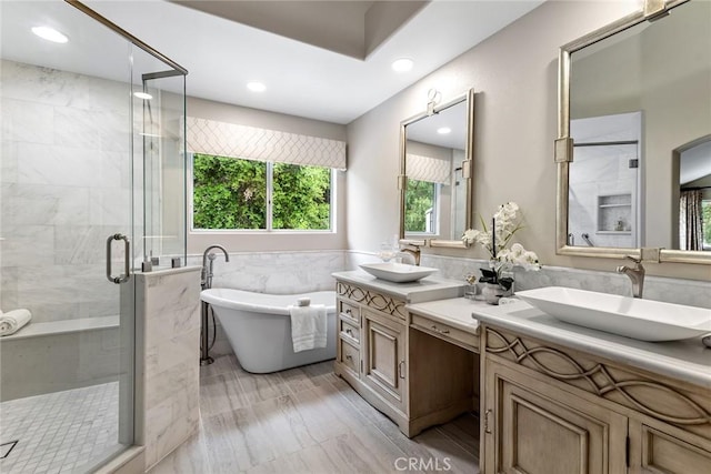 full bath featuring a freestanding tub, tile walls, a shower stall, and a sink
