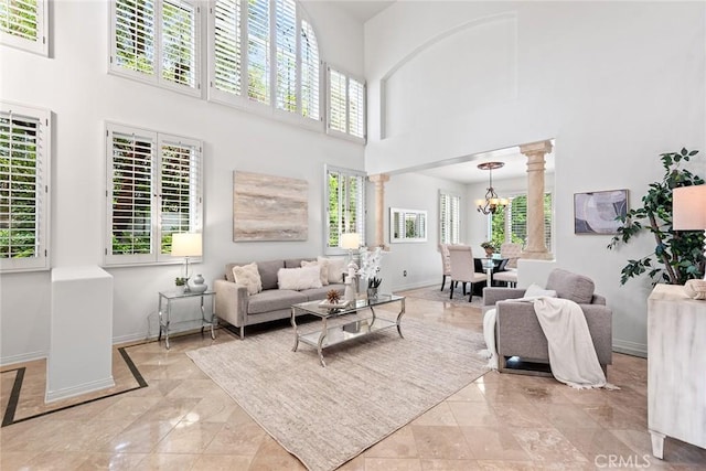 living area featuring ornate columns, a high ceiling, baseboards, and marble finish floor
