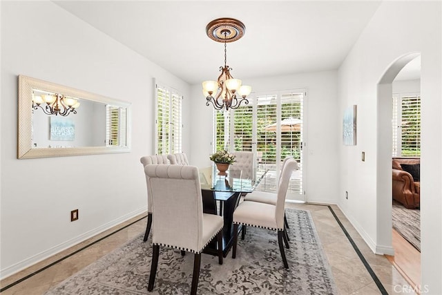 dining room featuring baseboards, arched walkways, light tile patterned floors, and a notable chandelier
