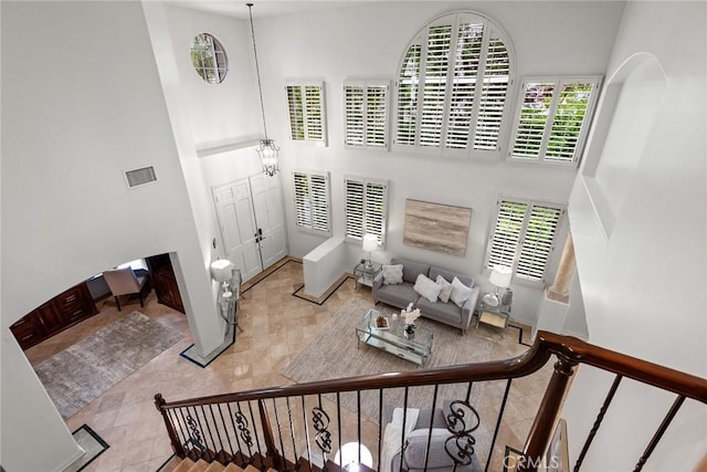 tiled living room featuring visible vents, a high ceiling, a wealth of natural light, and stairway