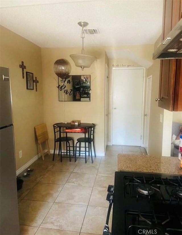 kitchen with stainless steel refrigerator, gas range, and light tile patterned floors