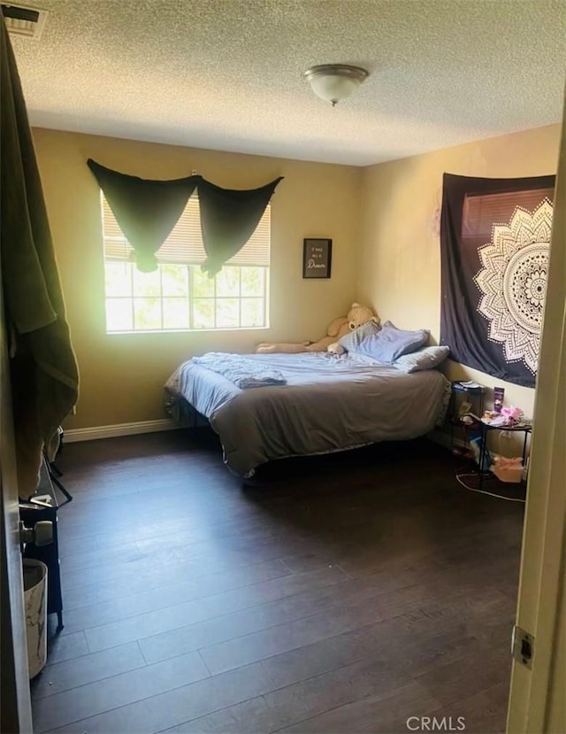 bedroom with dark hardwood / wood-style flooring and a textured ceiling