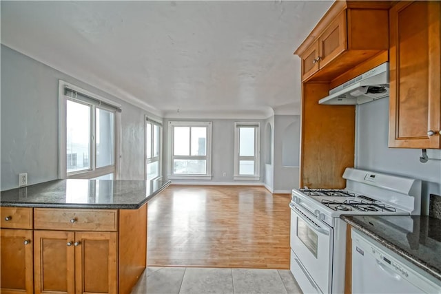 kitchen featuring light tile patterned flooring, white appliances, and dark stone counters