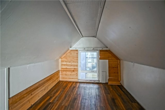 additional living space with dark wood-type flooring, wooden walls, and vaulted ceiling