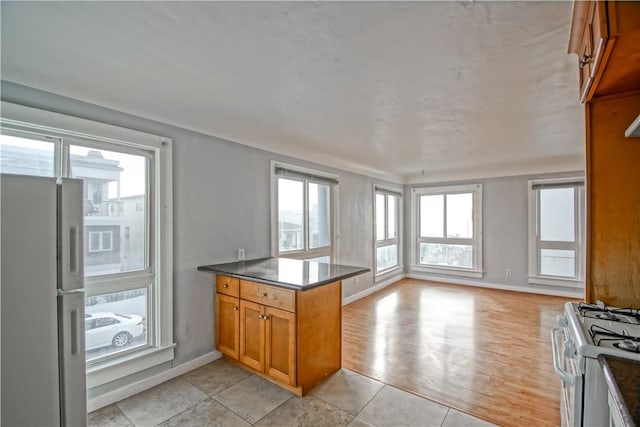 kitchen featuring white appliances, kitchen peninsula, and light tile patterned floors