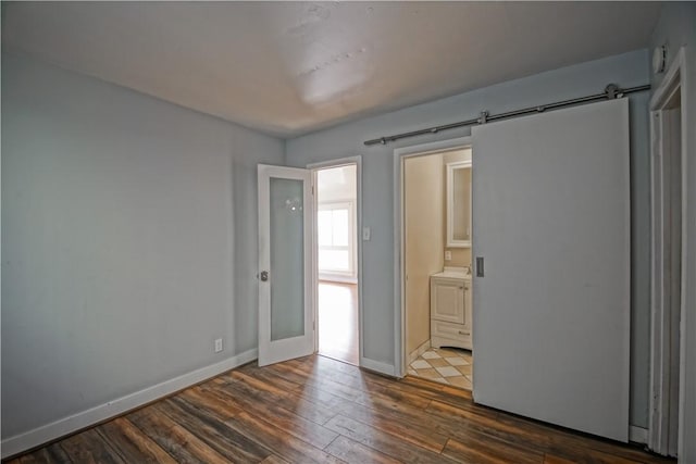 unfurnished room featuring washer / clothes dryer, a barn door, and dark hardwood / wood-style flooring