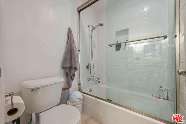 bathroom with tile patterned floors, toilet, and combined bath / shower with glass door