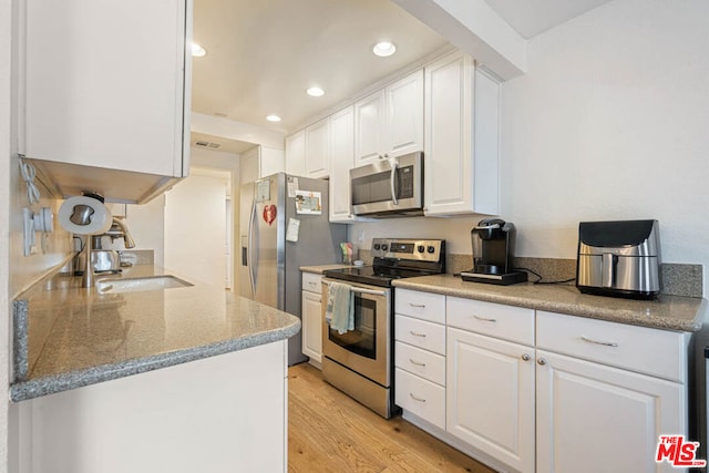 kitchen featuring white cabinetry, appliances with stainless steel finishes, sink, and light hardwood / wood-style flooring