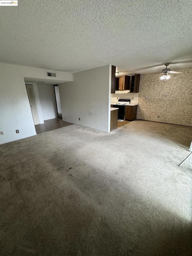 unfurnished living room with ceiling fan, a textured ceiling, and dark carpet