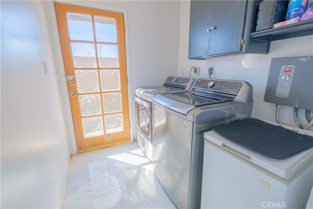 clothes washing area with cabinets, light tile patterned floors, and washer and clothes dryer