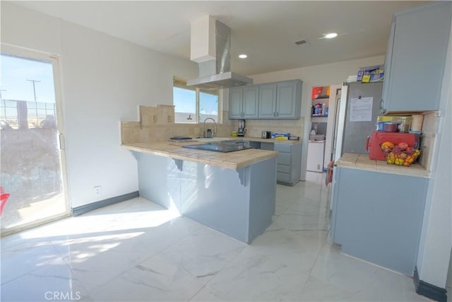 kitchen featuring a breakfast bar area, independent washer and dryer, tasteful backsplash, extractor fan, and kitchen peninsula