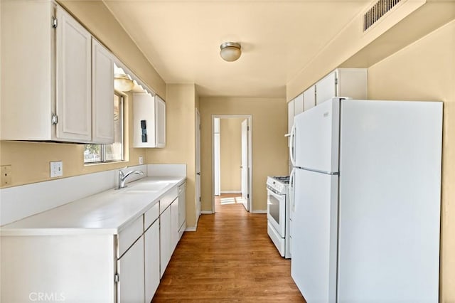 kitchen with white cabinetry, white appliances, light hardwood / wood-style floors, and sink