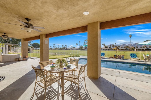 view of patio / terrace featuring a fenced in pool, a mountain view, and ceiling fan