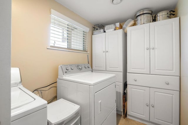 washroom featuring cabinets, washing machine and dryer, and light tile patterned floors