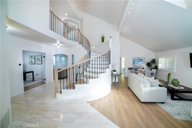 living room with beamed ceiling, light wood-type flooring, and high vaulted ceiling