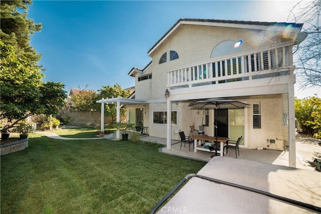 rear view of house featuring a balcony, a pergola, a lawn, and a patio area