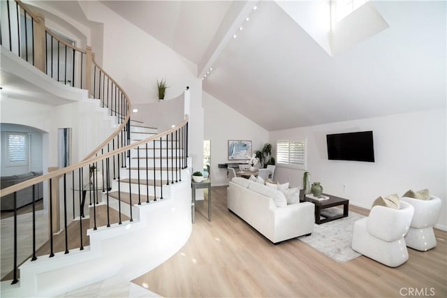 living room with beam ceiling, high vaulted ceiling, and light hardwood / wood-style floors