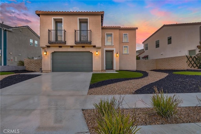 mediterranean / spanish-style house featuring a balcony, a garage, fence, concrete driveway, and stucco siding