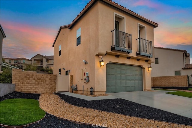 exterior space with a balcony, a tile roof, concrete driveway, and stucco siding