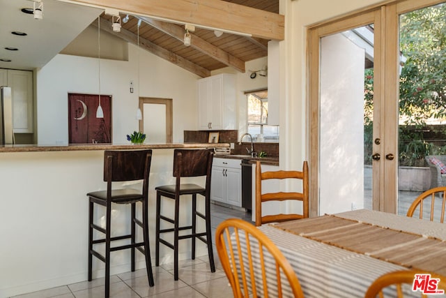 kitchen with white cabinetry, vaulted ceiling with beams, wood ceiling, and a wealth of natural light