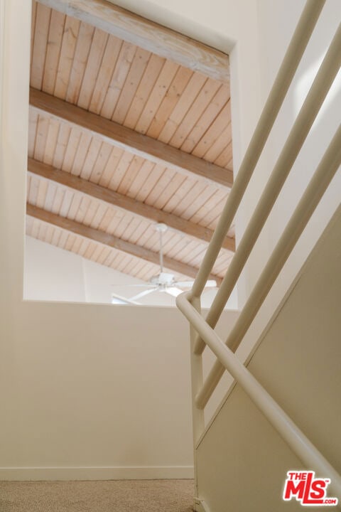 interior space featuring beamed ceiling, carpet, and ceiling fan