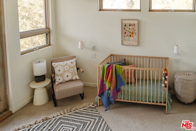 carpeted bedroom featuring a nursery area