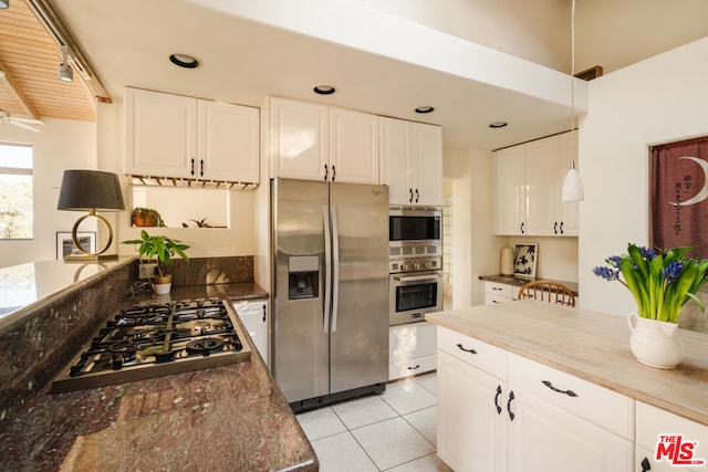 kitchen with light tile patterned flooring, appliances with stainless steel finishes, butcher block countertops, white cabinets, and hanging light fixtures