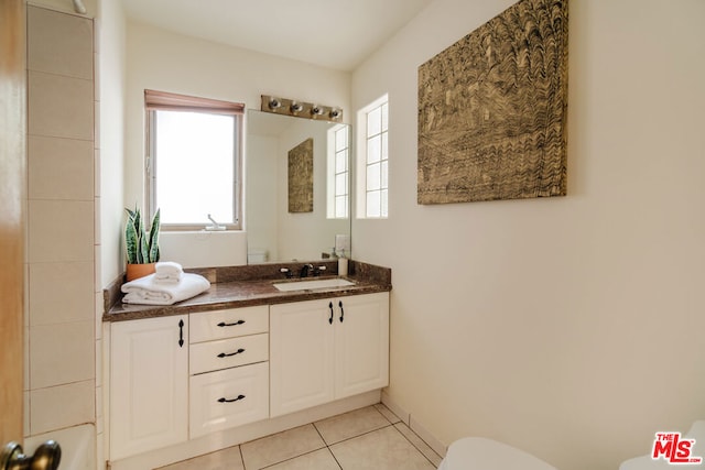 bathroom featuring a healthy amount of sunlight, toilet, tile patterned flooring, and vanity