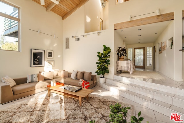 tiled living room featuring beam ceiling, plenty of natural light, wooden ceiling, and high vaulted ceiling