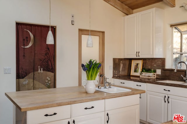 kitchen with pendant lighting, white cabinetry, wooden counters, and sink