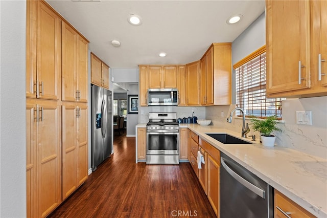 kitchen with stainless steel appliances, dark hardwood / wood-style flooring, light stone countertops, and sink