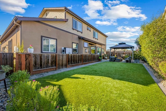 back of property with a yard and a gazebo