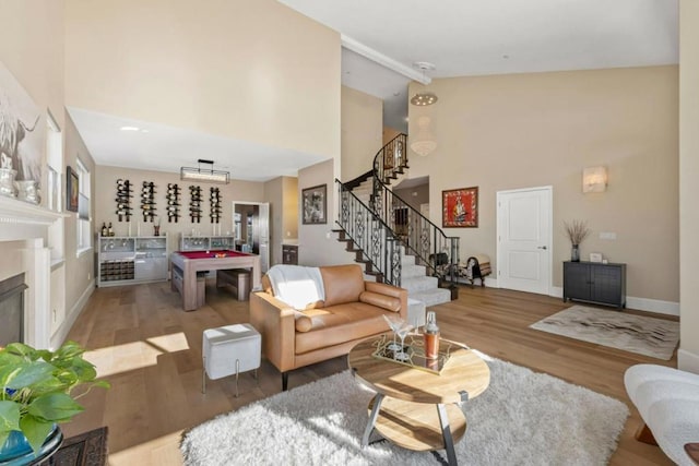 living room with hardwood / wood-style flooring, pool table, and high vaulted ceiling