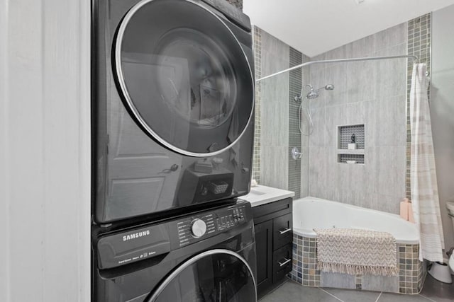 laundry area featuring cabinets, stacked washer and clothes dryer, and light tile patterned floors