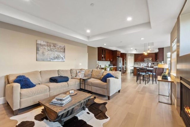 living room with light hardwood / wood-style floors and a raised ceiling