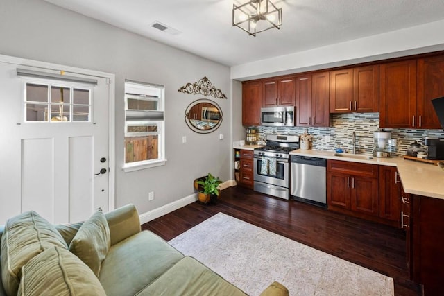 kitchen with sink, backsplash, dark hardwood / wood-style floors, and appliances with stainless steel finishes