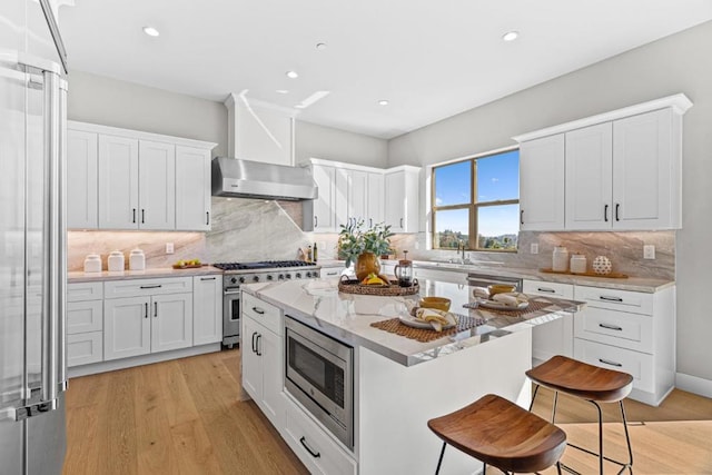 kitchen with light stone counters, a center island, appliances with stainless steel finishes, a kitchen breakfast bar, and white cabinets