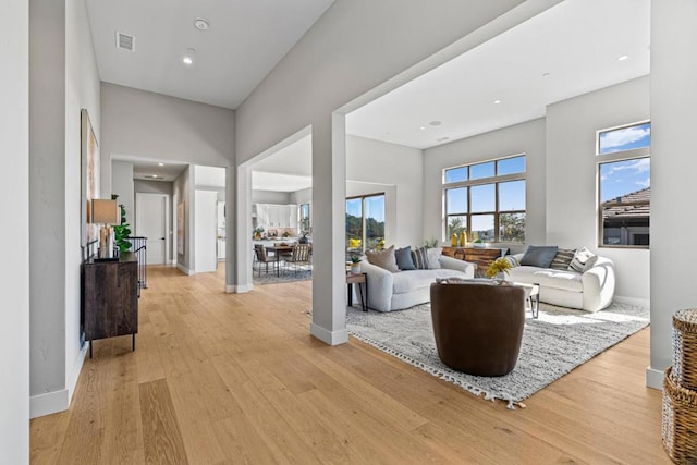 living room with light hardwood / wood-style floors and a high ceiling