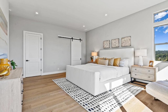 bedroom with light hardwood / wood-style flooring and a barn door