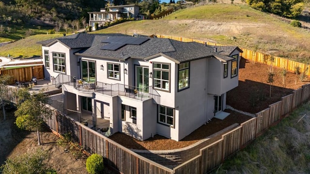 back of house featuring solar panels and a balcony